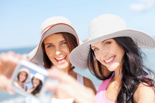 summer holidays and vacation concept - girls taking self portrait on the beach